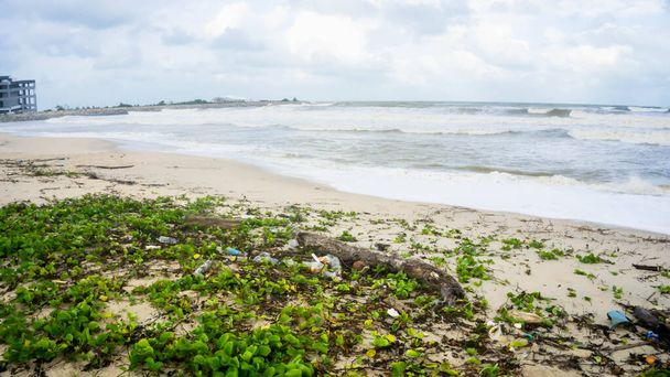 Kirli sahili olan güzel bir okyanus manzarası. Kuala Terengganu 'daki Batu Burok Sahili' nde plastik çöp ve tıbbi atık malzemeleriyle kumlu sahilde büyük bir mavi okyanus dalgası. Görüntü biraz bulanık. - Fotoğraf, Görsel