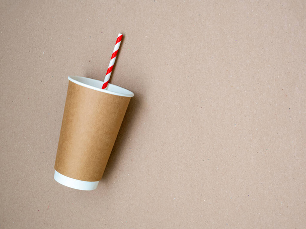 Takeaway coffee mug with paper white and red drinking straw on craft paper background. The concept of a world without plastic and a clean planet. Space for text. Zero waste. Flat lay, top view - Foto, Imagen