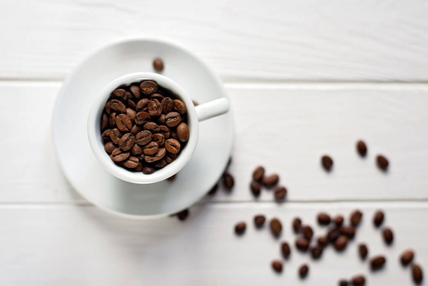 Cup of aromatic coffee in beans on a white wooden background. Flat lay. - Foto, Bild