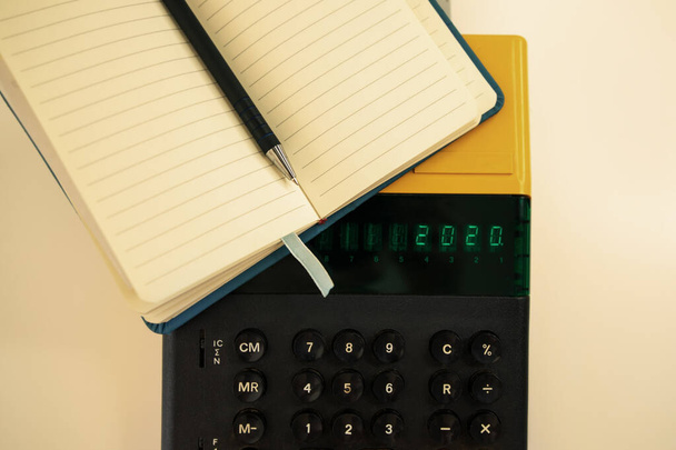 Oude computer model uit de jaren 80 op een witte achtergrond, het is ingeschakeld schrijft 2020 en een notitieboek met een pen klaar voor notities. - Foto, afbeelding