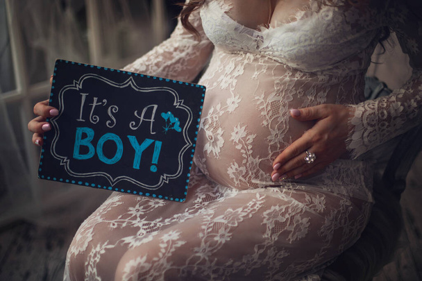 The future mother poses with her belly and the sign she writes on " its a boy" - Photo, Image