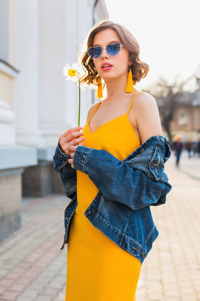 beautiful sexy stylish woman in yellow stylish dress wearing denim jacket, trendy outfit, spring summer fashion trend, sunny, blue sunglasses, street fashion, hipster style, fashionable accessories - Fotoğraf, Görsel