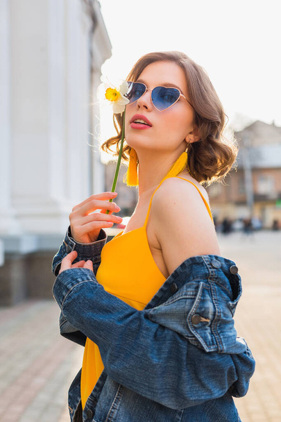beautiful sexy stylish woman in yellow stylish dress wearing denim jacket, trendy outfit, spring summer fashion trend, sunny, blue sunglasses, street fashion, hipster style, fashionable accessories - Фото, зображення