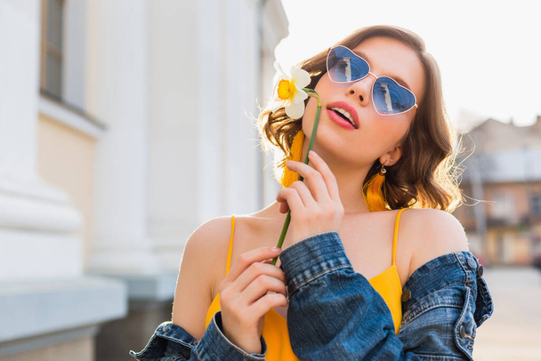 beautiful sexy stylish woman in yellow stylish dress wearing denim jacket, trendy outfit, spring summer fashion trend, sunny, blue sunglasses, street fashion, hipster style, fashionable accessories - Zdjęcie, obraz