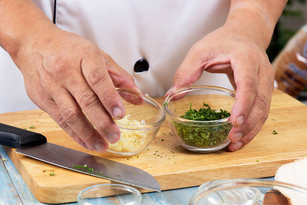 Chef hold csésze apróra vágott petrezselyem és fokhagyma szakács fokhagymás kenyér / Fokhagymás kenyér koncepció - Fotó, kép