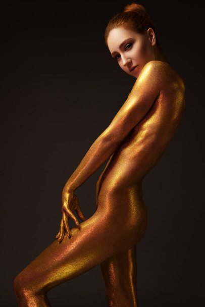 sexy girl gold-plated glittering posing - Foto, afbeelding