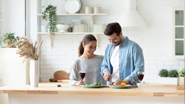 Happy millennial couple cooking at home together - Photo, image