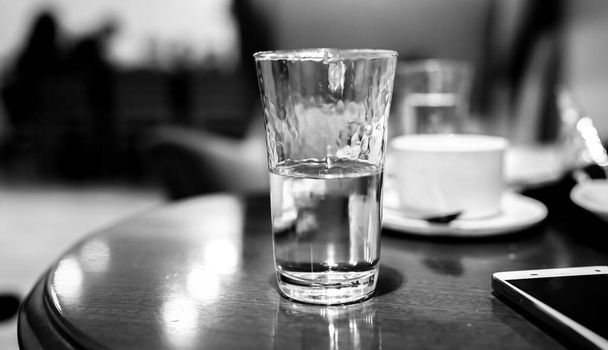 nakrycie stołu w restauracji, szklanka wody na kawę, szklanka wody, koncepcja czarno-biała, uzależnienie od alkoholu, wieczór w barze, depresja - Zdjęcie, obraz