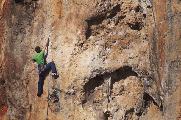 Um homem forte supera uma rota de escalada difícil em um terreno natural. O alpinista treina nas rochas turcas. Estilo de vida ativo. Passatempo extremo
. - Foto, Imagem