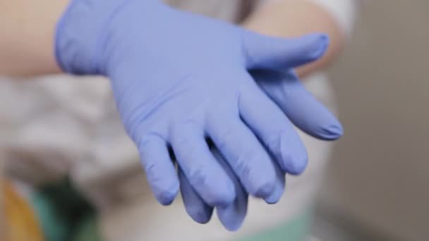 Professional beautician treats blue rubber gloves with an antiseptic - Felvétel, videó