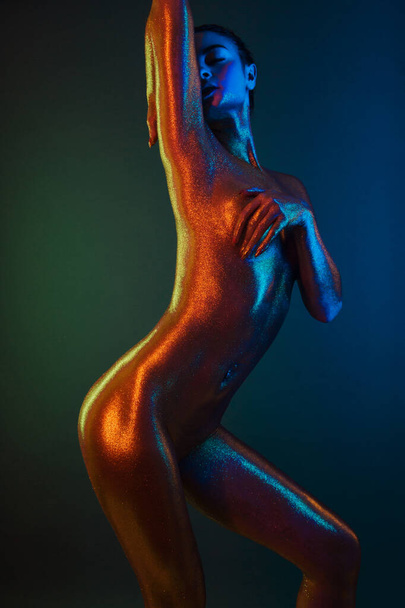 sexy girl gold-plated glittering posing in neon light - Фото, изображение
