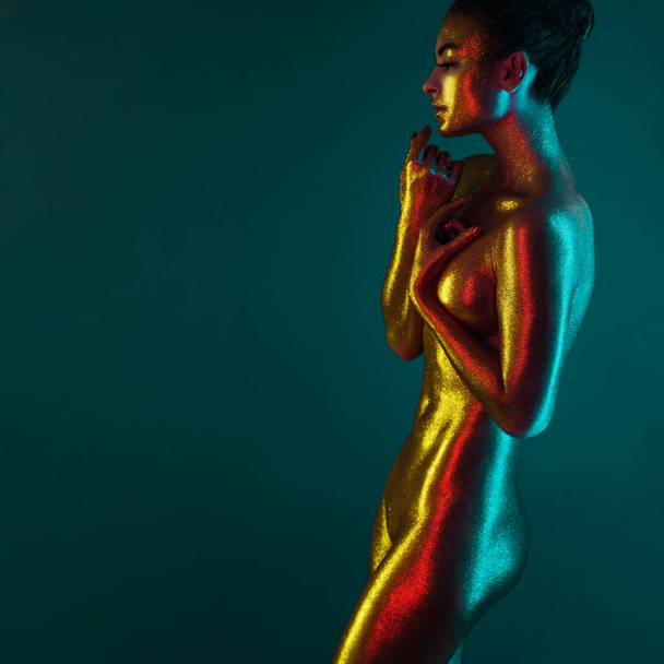 sexy girl gold-plated glittering posing in neon light - Fotoğraf, Görsel