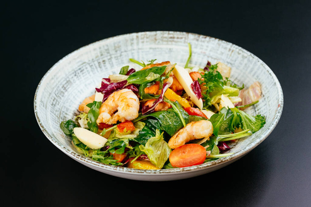 bunter Salat mit Garnelen, Gemüse und Tomaten auf blauem Teller - Foto, Bild