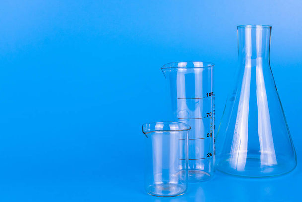 Medical laboratory glassware on blue background. Copy space. - 写真・画像