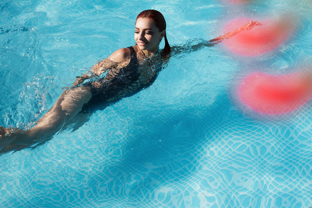 fashion photo of a sexy beautiful girl in elegant bikini posing and takes a sunbath in the swimming pool - Photo, Image