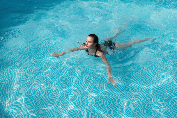 fashion photo of sexy beautiful girl with brunette hair in elegant bikini posing and takes a sunbath in the swimming pool - Фото, изображение