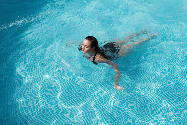 fashion photo of sexy beautiful girl with brunette hair in elegant bikini posing and takes a sunbath in the swimming pool - Φωτογραφία, εικόνα