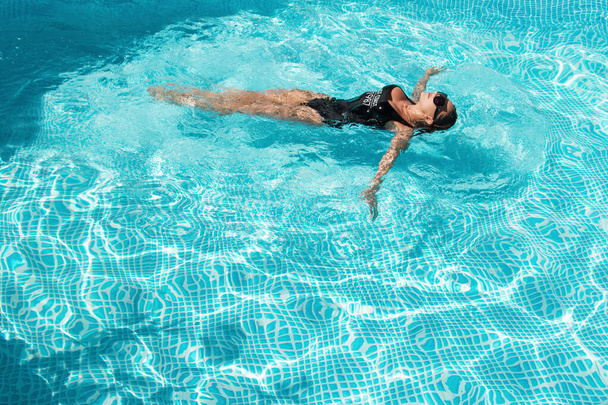 fashion photo of sexy beautiful girl with brunette hair in elegant bikini posing and takes a sunbath in the swimming pool - Foto, Bild