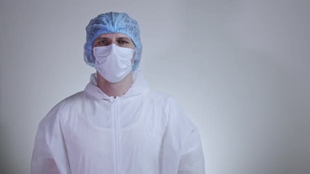 Close-up of young male doctor in the protective suit putting on surgical glasses. Concept of health care, hospitals or clinic and coronavirus pandemic  - Séquence, vidéo