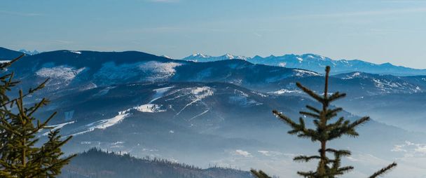 csodálatos kilátás Magurka Wislanska hegy télen Beskid Slaski hegyek Lengyelországban alacsonyabb dombok Beskid Zywiecki hegyek és magasabb csúcsok Tatra hegyek a háttérben - Fotó, kép