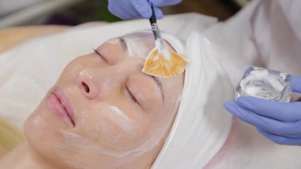Profesjonalny kosmetyk nakładający maskę na twarz kobiecie. - Materiał filmowy, wideo