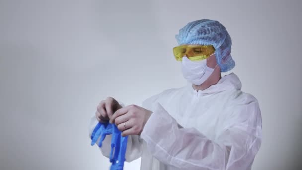 Close-up of young male doctor in the protective suit putting on surgical gloves. Concept of health care, hospitals or clinic and coronavirus pandemic  - Metraje, vídeo
