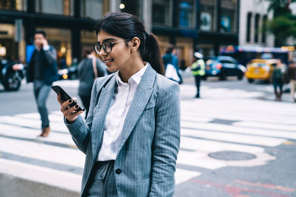 Нарядный владелец бизнеса в оптической экипировке читает входящую электронную почту с финансовым отчетом, умная женщина-трейдер в классических очках набирает контактный номер через приложение для смартфона - Фото, изображение