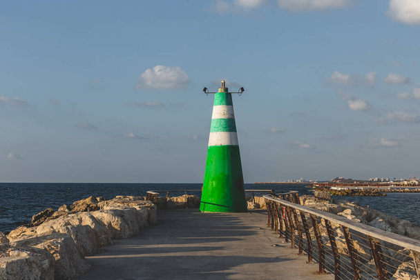 Зелено-белый полосатый маяк у входа в Тель-Авивскую гавань. Маяки отмечают опасные береговые линии, отмели, рифы, скалы и безопасные входы в гавани; они также помогают в аэронавигации.
 - Фото, изображение