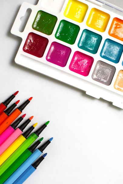A palette of color watercolors with brushes and markers on a white background with space for text. Creative classes with children at home and at school, art master class, the concept of creative development. Desktop of the creative workshop-flatlay - Фото, изображение