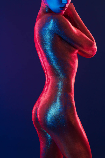 sexy girl gold-plated glittering posing in neon light - Фото, изображение