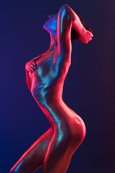 sexy girl gold-plated glittering posing in neon light - Photo, Image