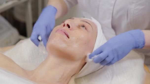 Esthéticienne professionnelle lave le masque sur le visage d'une femme. - Séquence, vidéo