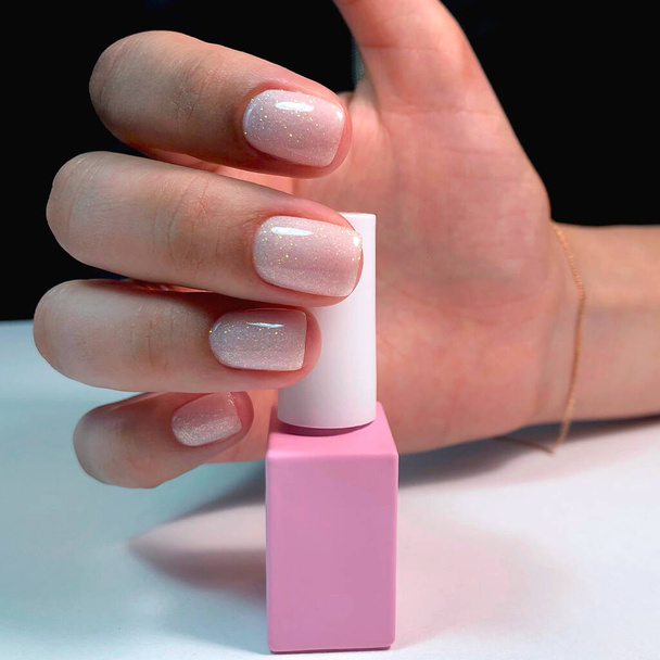 Manicure. Beautiful manicured woman's hands with pink nail polish. Bottle of nail polish.Trendy pink nails - Photo, image