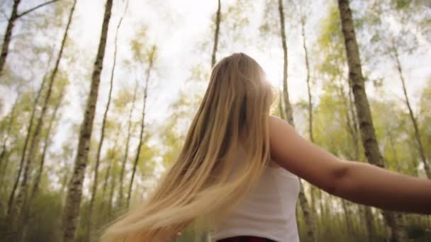 Kaunis onnellinen nuori valkoihoinen nainen pyörii metsässä. Vapauden käsite
 - Materiaali, video