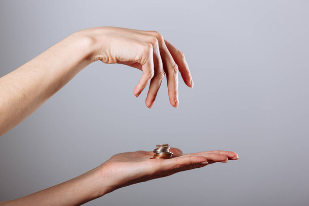 Dłoń kobiety dając lub biorąc złotą monetę do innej strony na odizolowanym białym tle, koncepcja kryzysu. - Zdjęcie, obraz