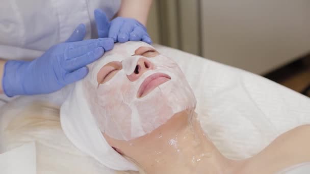 Professionelle legt der Kundin Gesichtsmaske auf. Kosmetologie. - Filmmaterial, Video