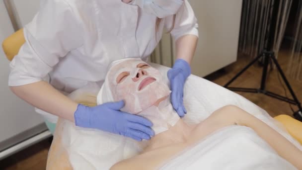 Profesional pone mascarilla facial a cliente mujer. Cosmetología
. - Imágenes, Vídeo