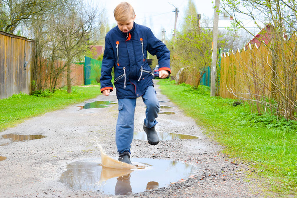 Boy child runs into a wet puddle. Funny walk. - Foto, Bild
