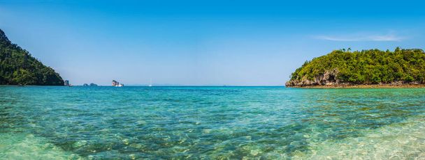 Panoramic view of the clear turquoise waters and lush Ko Kai island in Thailand with sailboats in the distance - Photo, Image