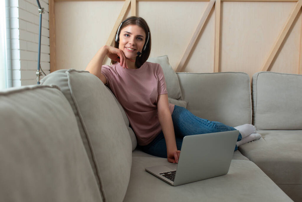 Happy young lady is sitting on sofa with gadget - Photo, image
