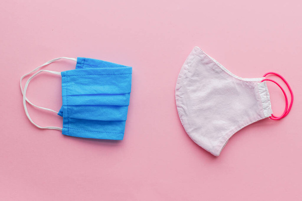 Reusable face mask and medical single use mask on pink background flat lay. Zero waste concept during coronavirus outbreak. Disposable mask and handmade textile mask - Фото, зображення