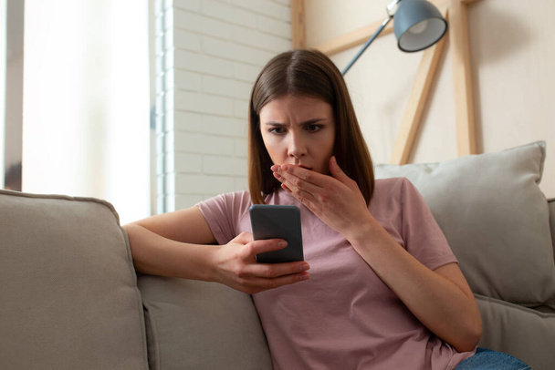 Female reading terrible news on her smartphone - Photo, Image