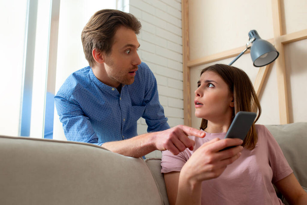 Shocked female is watching video on smartphone - Foto, afbeelding