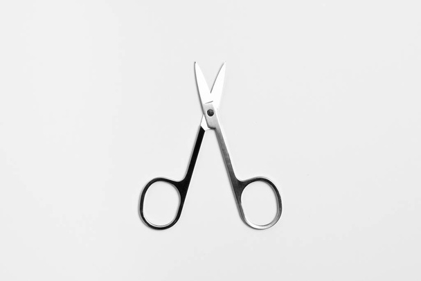 Small stainless steel scissors. Used for cutting nose hair and eyebrow decoration. Cosmetology equipment on a white background.High-resolution photo. - Foto, Imagen