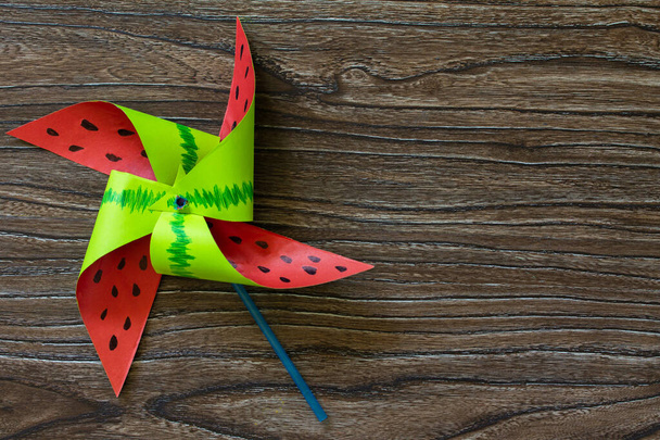 Fun toy watermelon windmill spinning on a wooden table. Children's art project, needlework, crafts for children - Фото, зображення