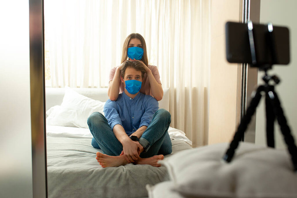 Lovers in blue masks making shot of themselves in bedroom - Фото, зображення