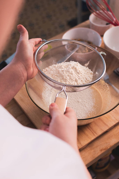 person sifting flour in the kitchen - Foto, imagen