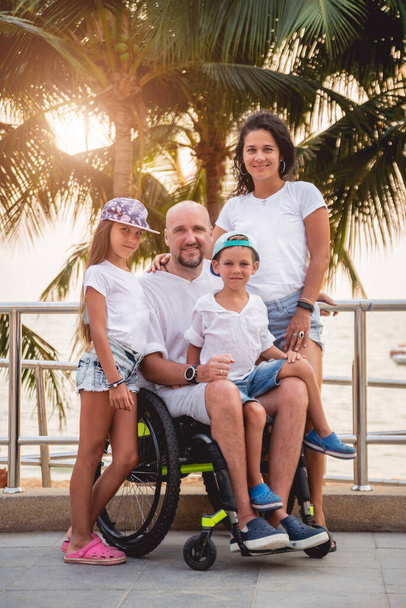 Disabled man in a wheelchair with his family on the beach. - Foto, Bild