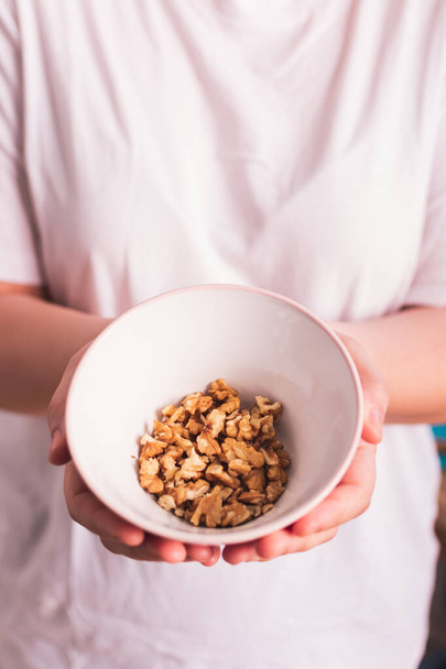 bowl of walnuts in the hands of a girl in the kitchen - Photo, image