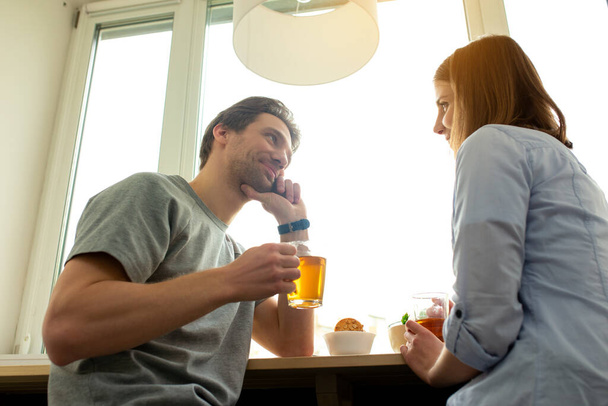 Young smiling spouses are enjoying tea indoors - Fotografie, Obrázek